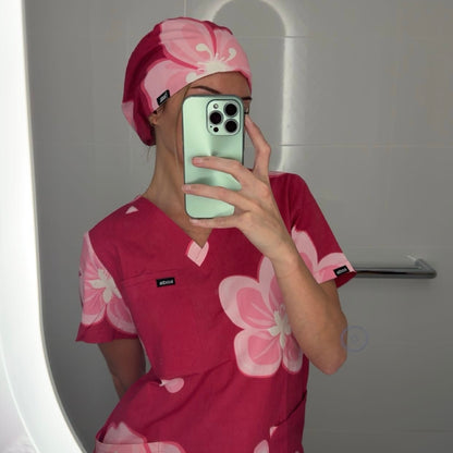 Person wearing a pink floral outfit and matching headscarf taking a mirror selfie.